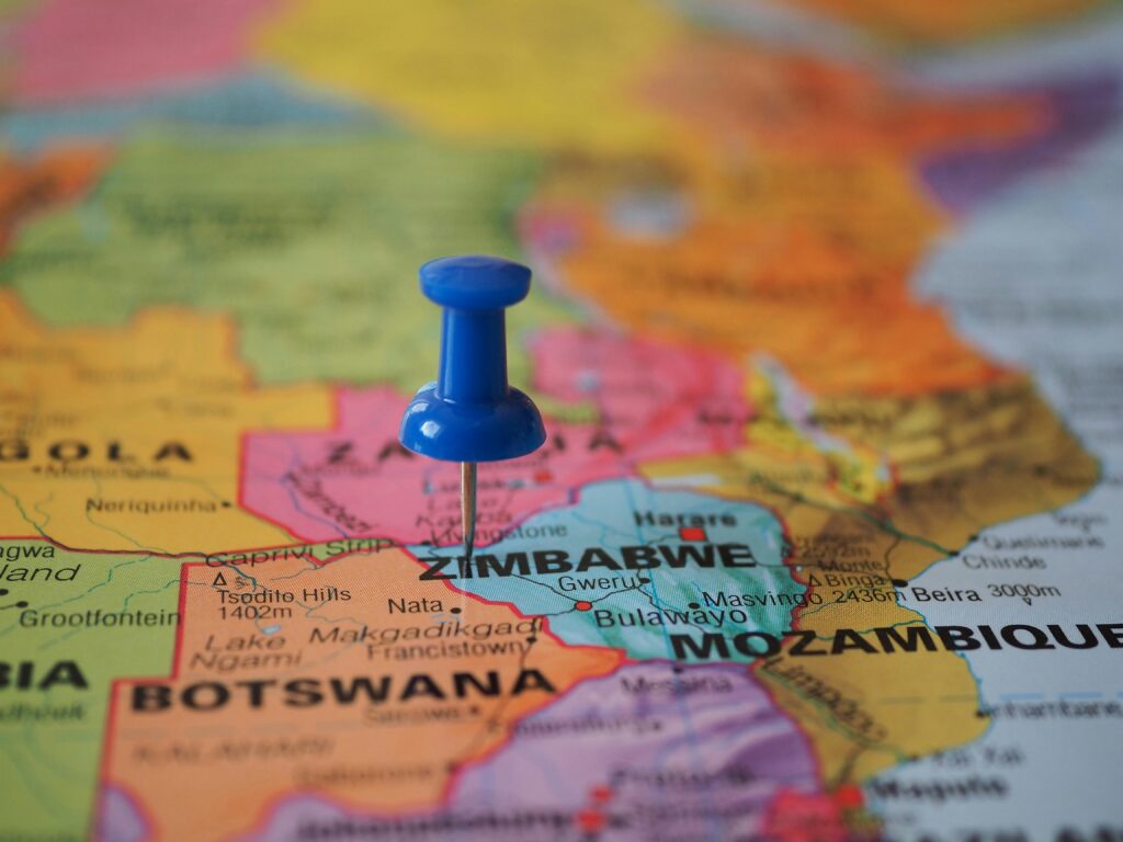 A blue pushpin marks Zimbabwe on a colorful close-up map highlighting its geographical position.