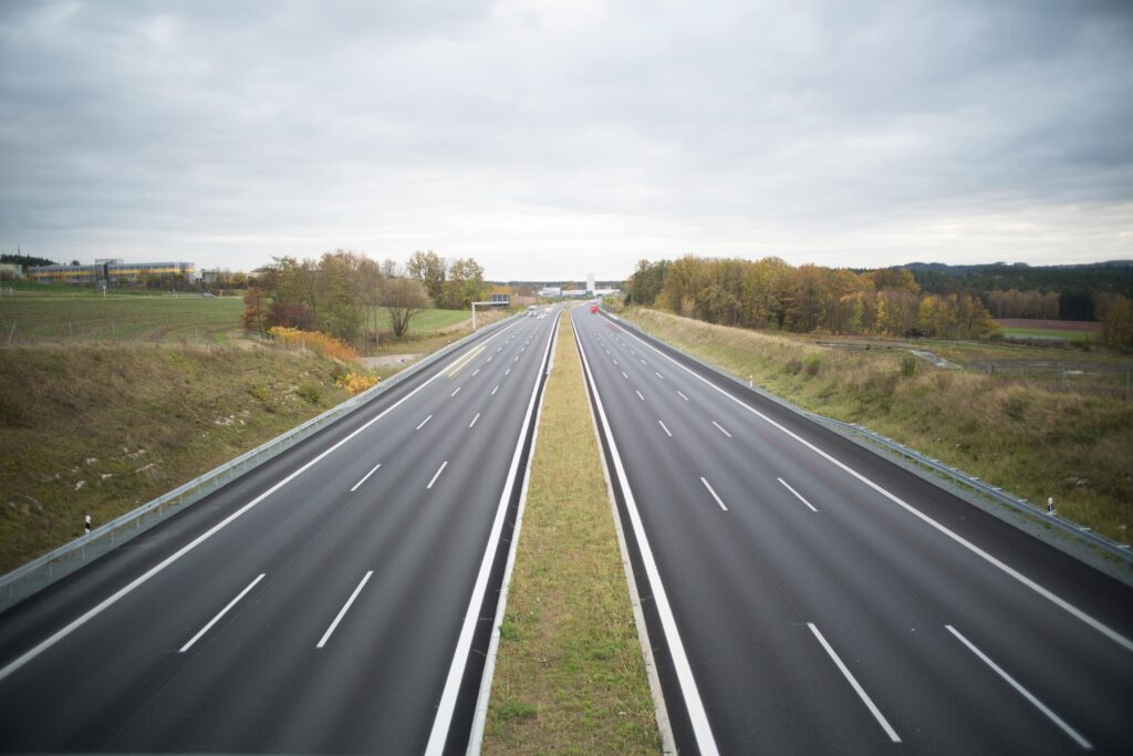 pexels-photo-967072-967072 A serene image of an empty highway stretching through a peaceful countryside under a cloudy sky.