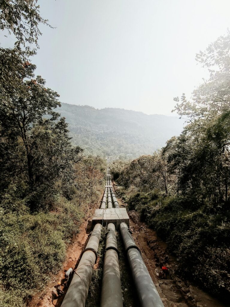 pexels-photo-8964873-8964873 Aerial view of a long pipeline stretching through a scenic mountain forest during summer, captured with natural lighting.